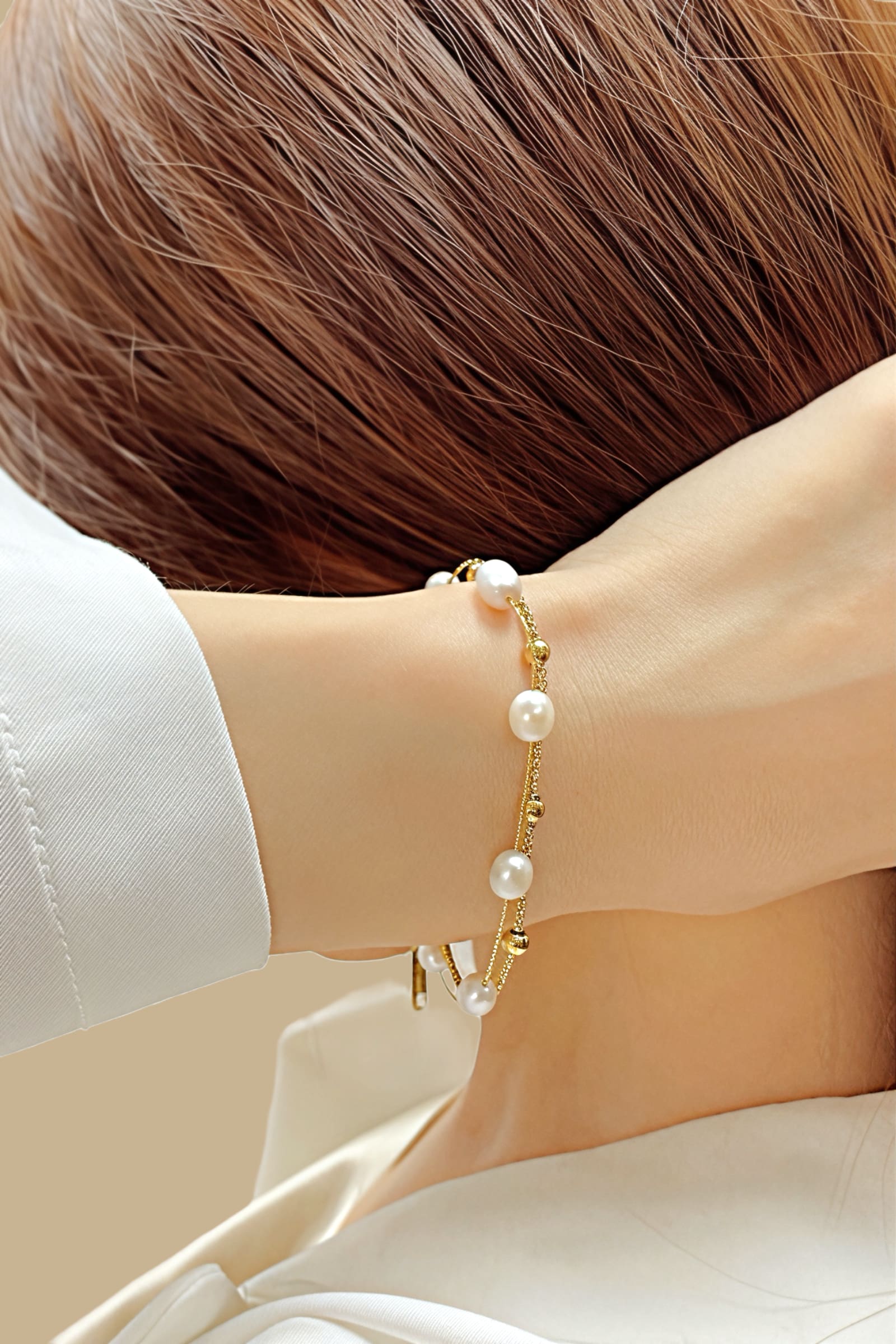 Top-view of GLISTIA’s Aurora bracelet featuring dual gold chains accented with polished beads and white pearls.