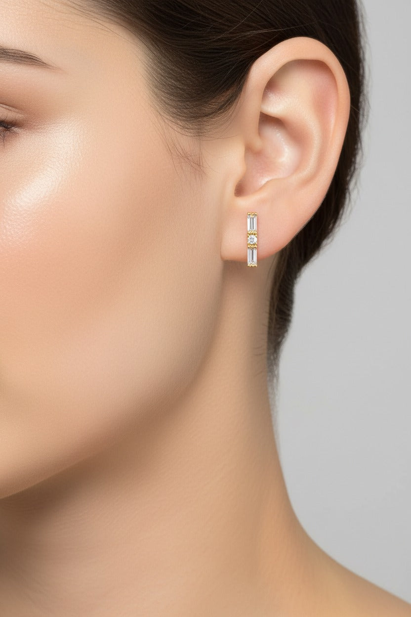 Baguette crystal piercing earrings crafted from stainless steel with 18K PVD gold plating, featuring baguette and round zircon crystals with barbell closure