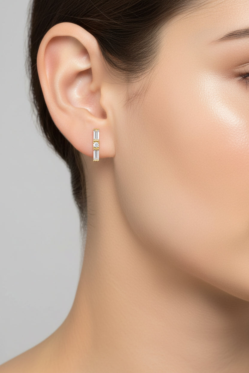 Close-up of baguette crystal piercing earrings highlighting baguette and round zircon stones with polished 18K PVD gold plated finish