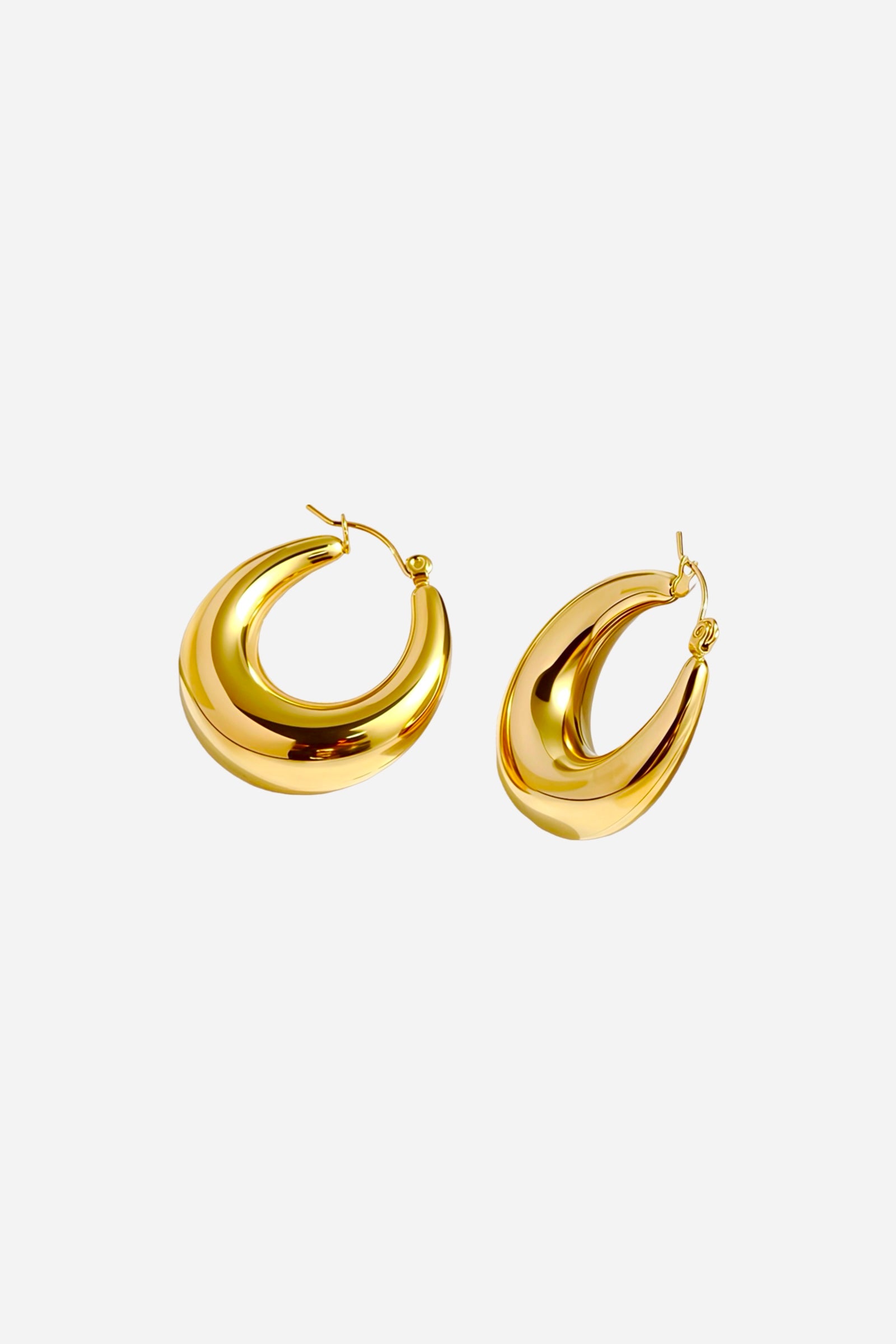 Angled view of bold crescent hoop earrings made from stainless steel with a high-polish PVD 18K gold plated finish, featuring sculptural curves and smooth reflective shine – GLISTIA.