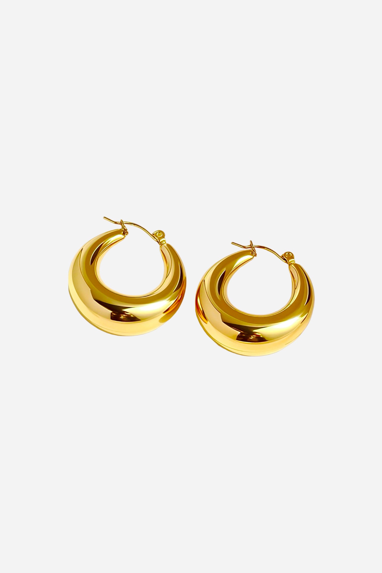 Pair of bold crescent hoop earrings crafted from stainless steel with a polished PVD 18K gold plated finish, featuring a smooth curved silhouette and high-shine reflective surface – GLISTIA.