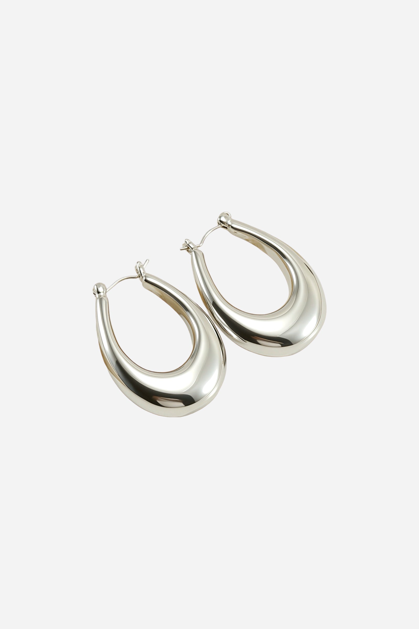 Angled top view of chunky silver hoop earrings featuring a sculpted teardrop shape, crafted from stainless steel with a mirror-polished silver tone finish – GLISTIA.