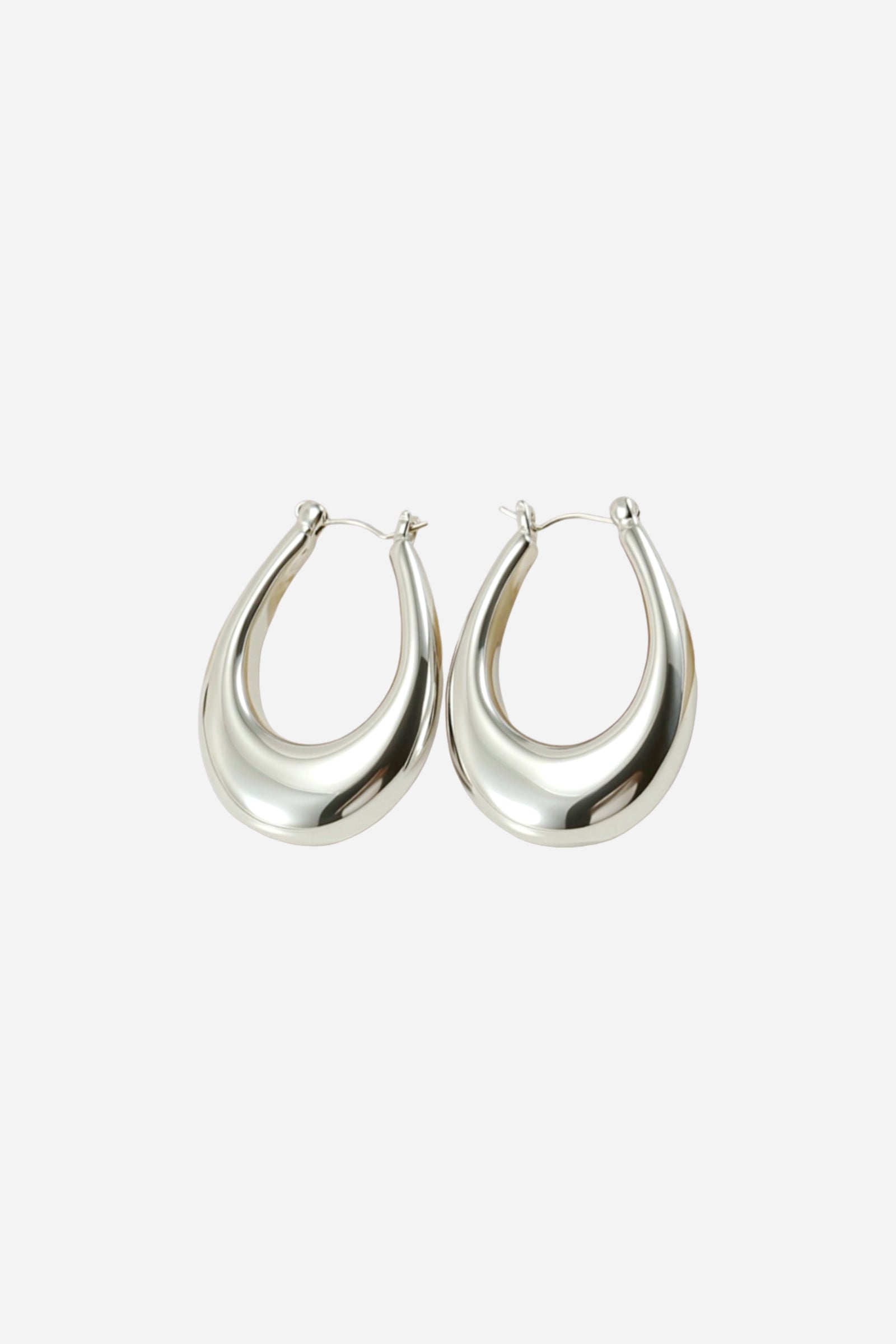 Angled view of chunky silver hoop earrings with a sculpted teardrop shape, crafted from stainless steel and finished in a reflective polished silver tone – GLISTIA.