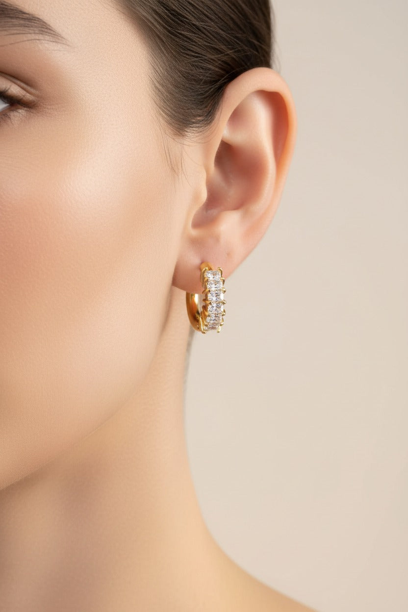 Close-up of cubic zirconia gold hoop earrings in 18K PVD gold plated stainless steel with prong set baguette and round stones