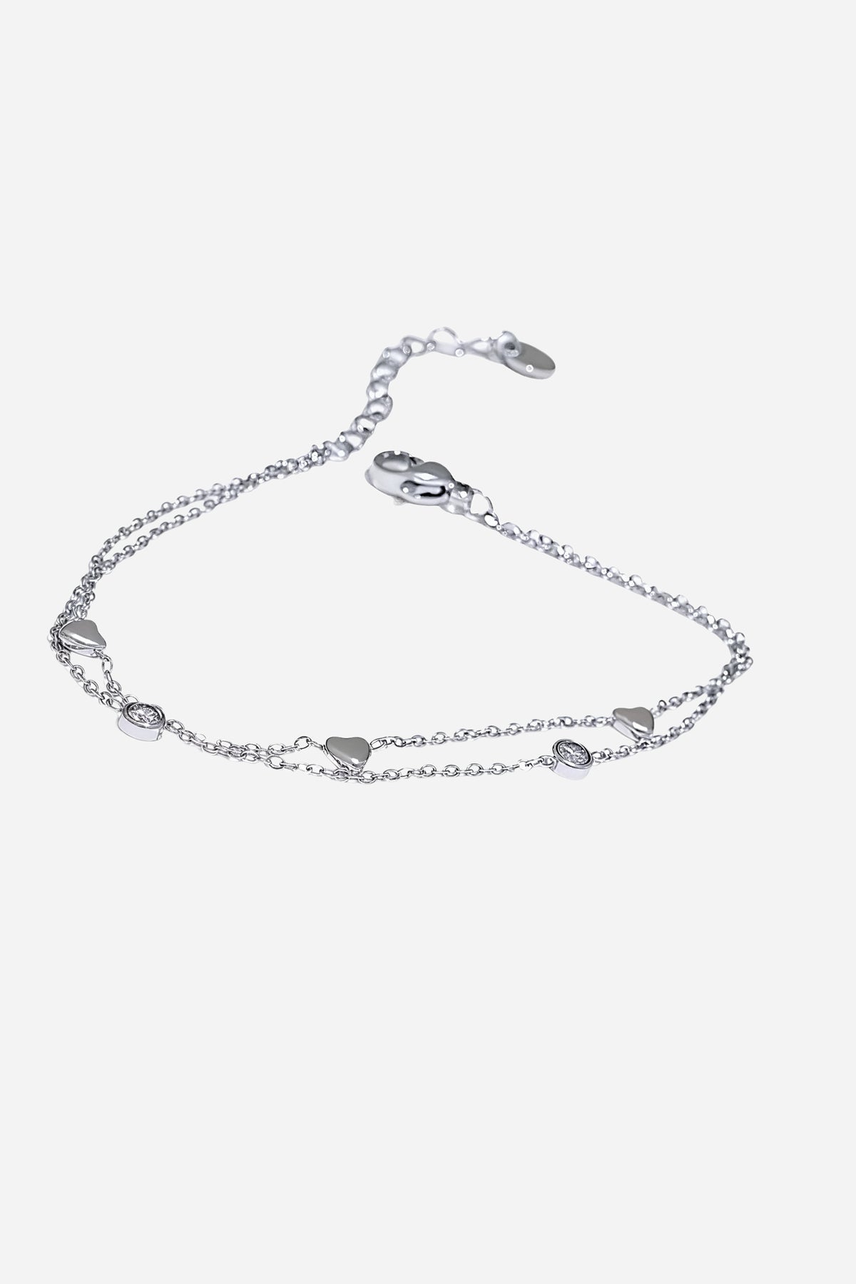 Top-view of GLISTIA’s delicate dual chain bracelet featuring mini heart charms and bezel-set crystal accents.