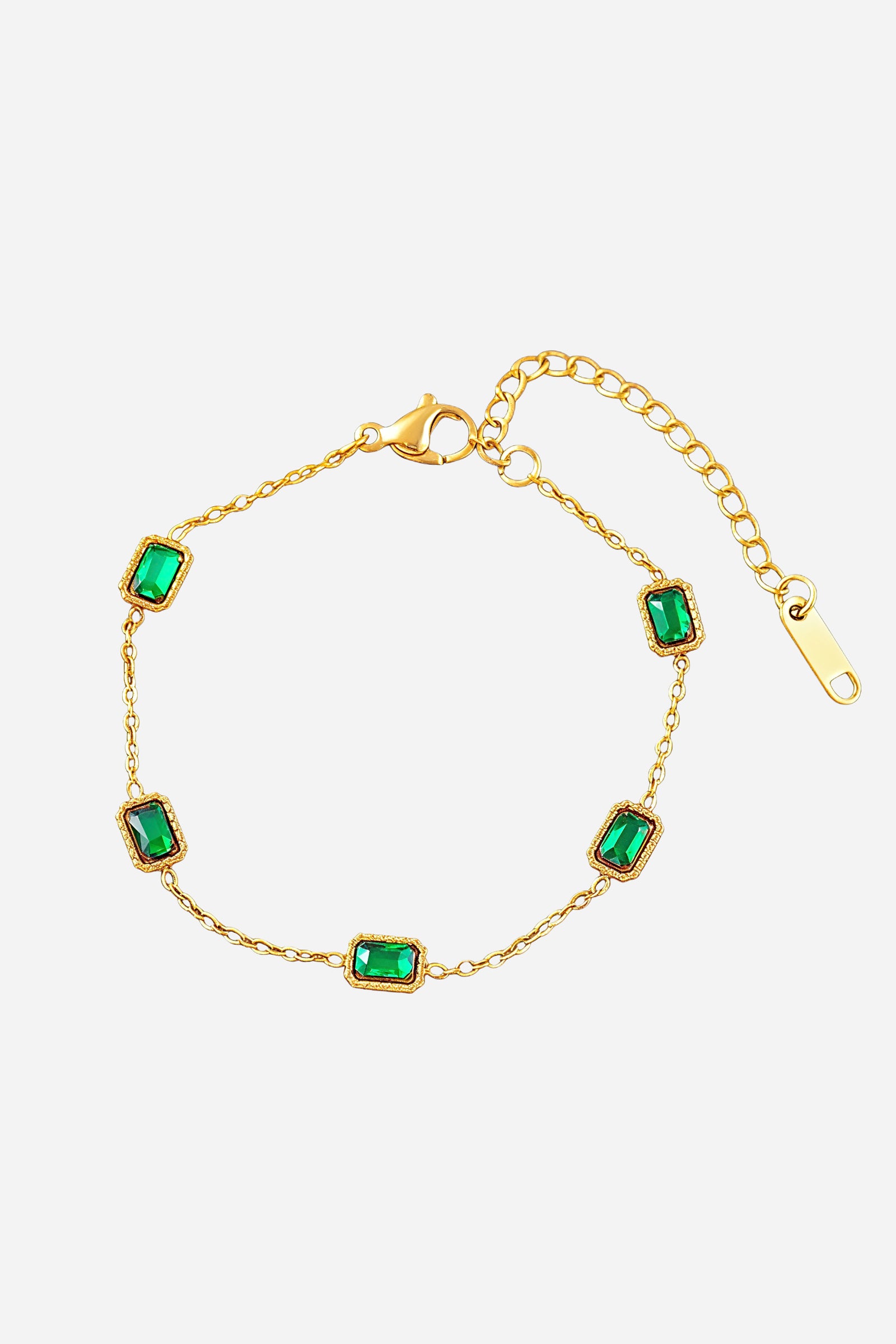Top-view of GLISTIA’s gold chain bracelet featuring evenly spaced rectangular emerald green stones.