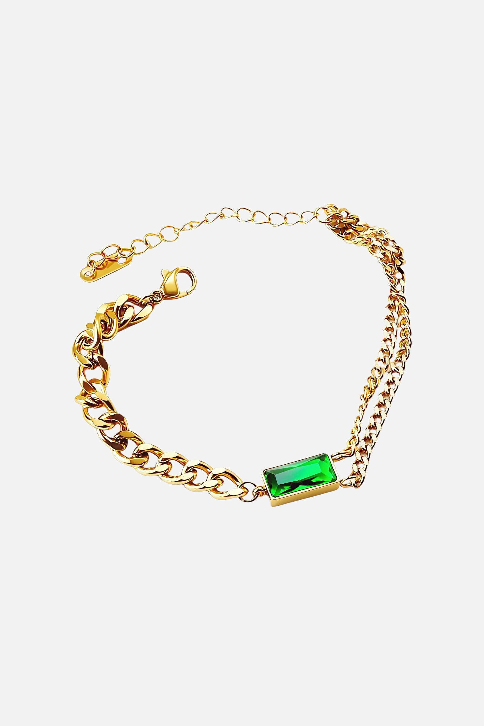 Top-view of GLISTIA’s Emerald Glow bracelet featuring a bold emerald-cut cubic zirconia set between dual gold chains.