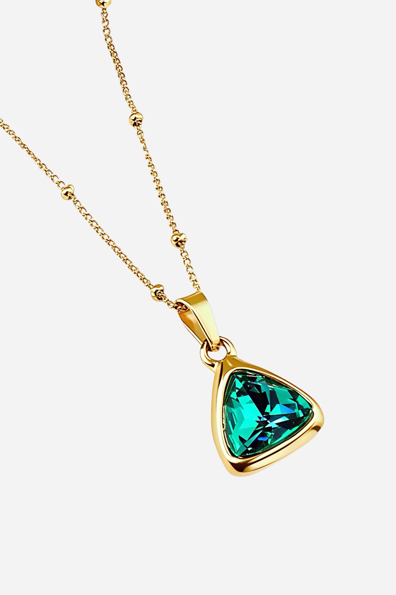 Close-up of GLISTIA Emerald Radiance Necklace featuring the vibrant emerald-cut pendant in a smooth gold bezel.