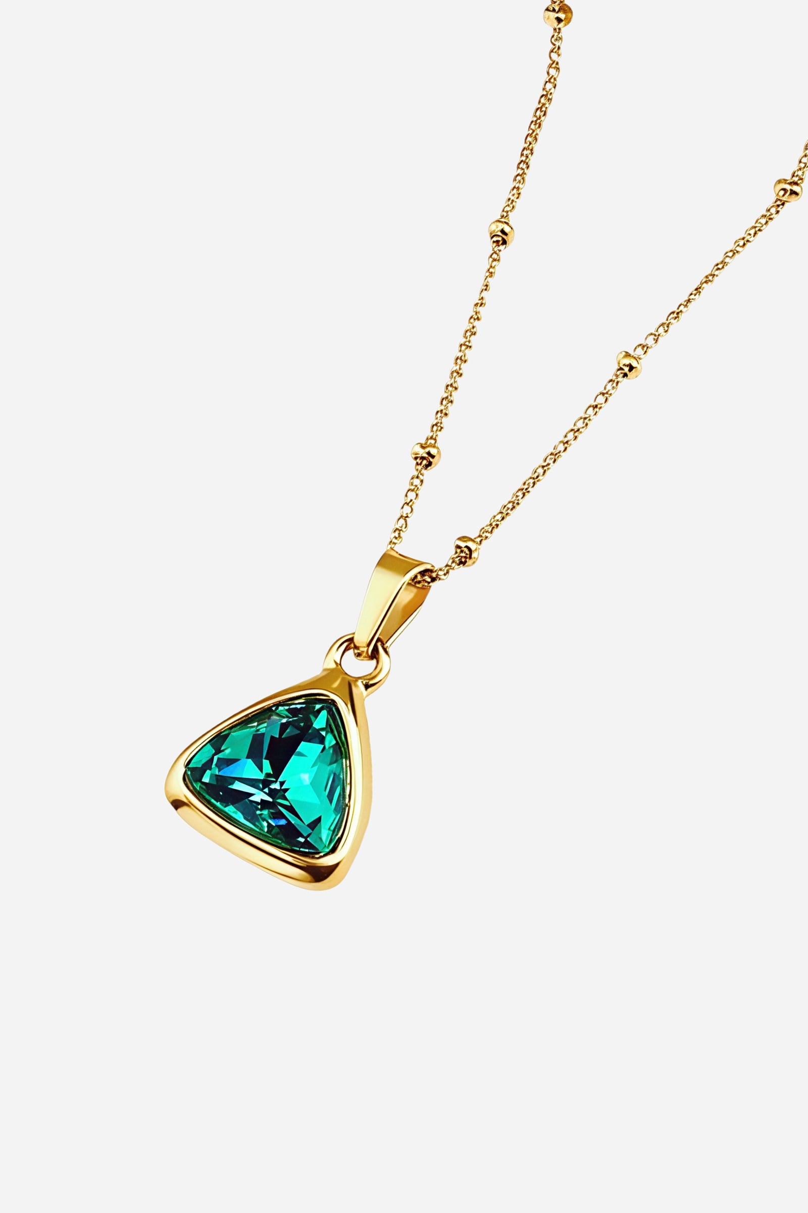 Side-angle view of GLISTIA Emerald Radiance Pendant highlighting the faceted green stone and gold frame.