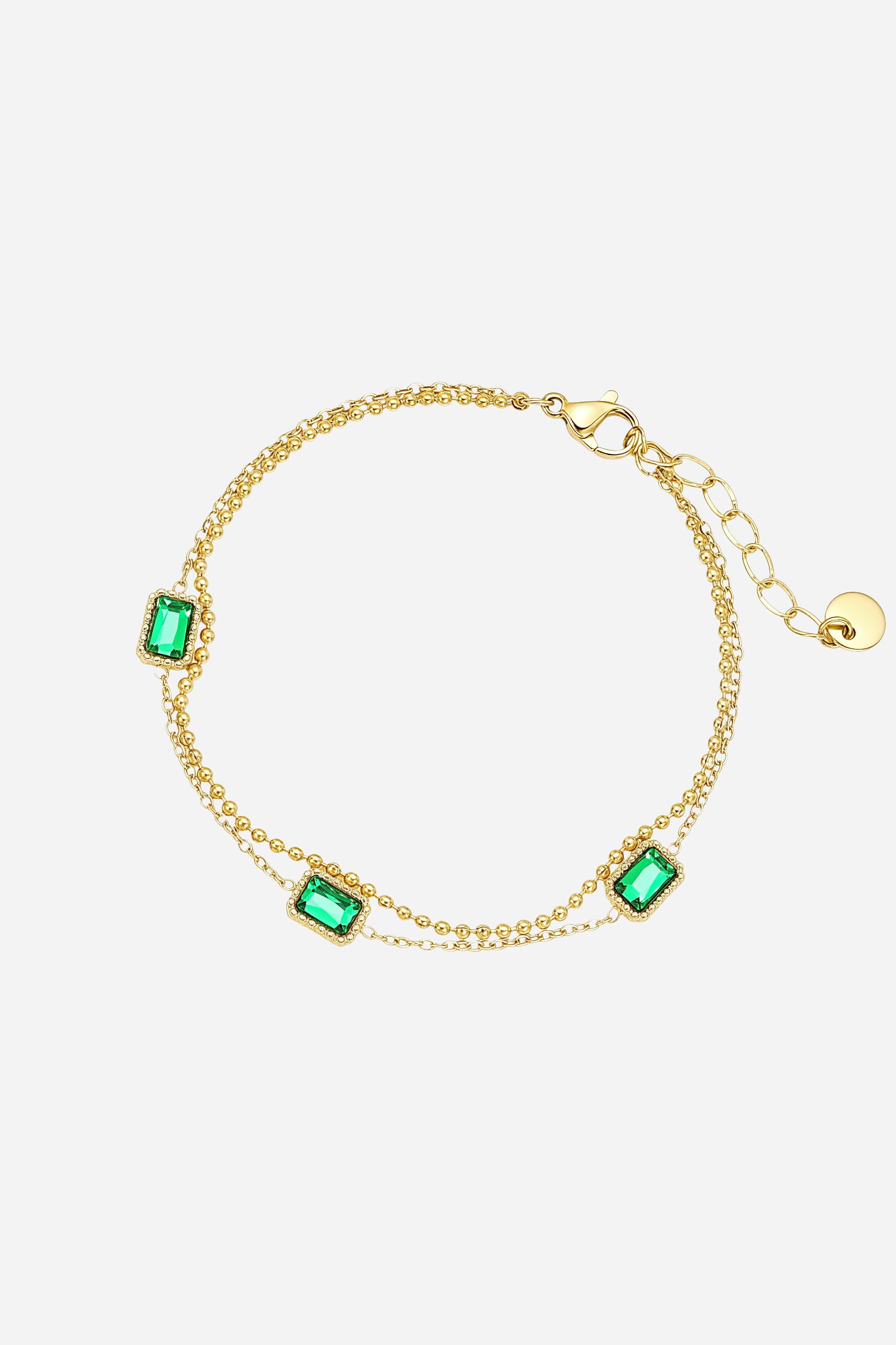 Top-view of GLISTIA’s gold chain bracelet featuring vibrant rectangular-cut green crystal stones.