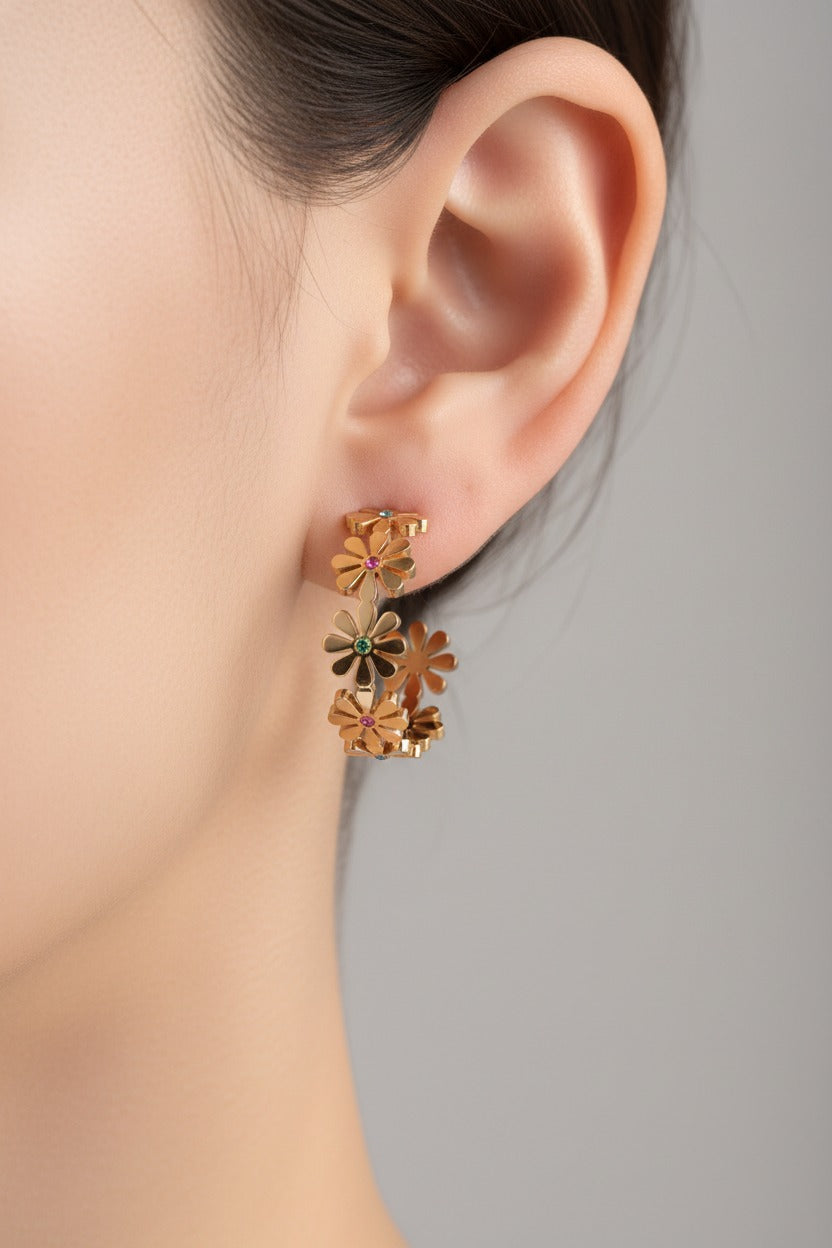 Floral daisy C hoop earrings worn on ear, crafted from stainless steel with 18K PVD gold plating and pastel crystal accents