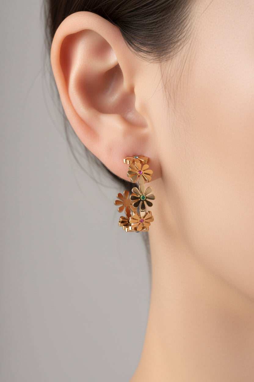 Side view of floral daisy hoop earrings in 18K PVD gold plated stainless steel with flower shaped charms and crystal detailing