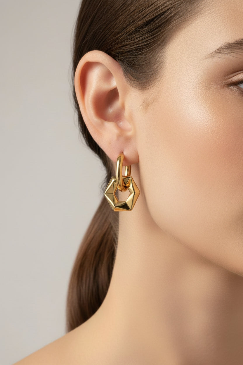 Geometric hexagon drop hoop earrings shown in side view, made from stainless steel with 18K PVD gold plating and a modern hexagon drop design.