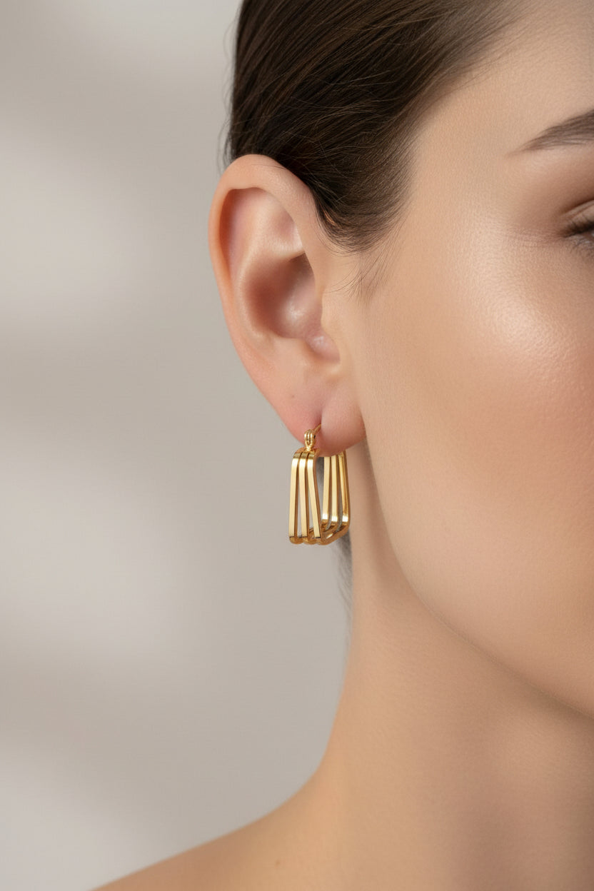 Geometric multi-bar hoop earrings in 18K PVD gold plated stainless steel worn on ear.