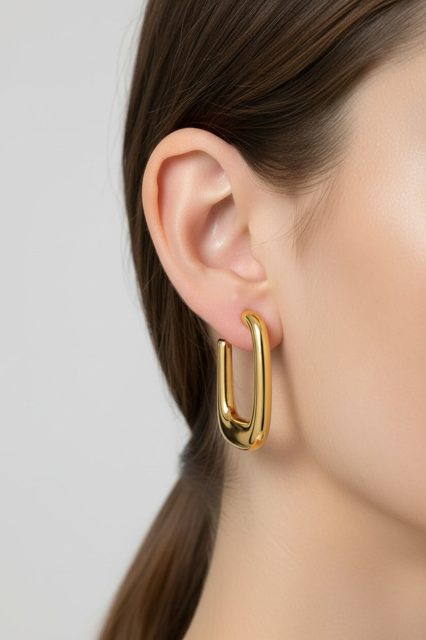 Geometric rectangular hoop earrings shown in side view, made from stainless steel with 18K PVD gold plating and a modern rectangular design.