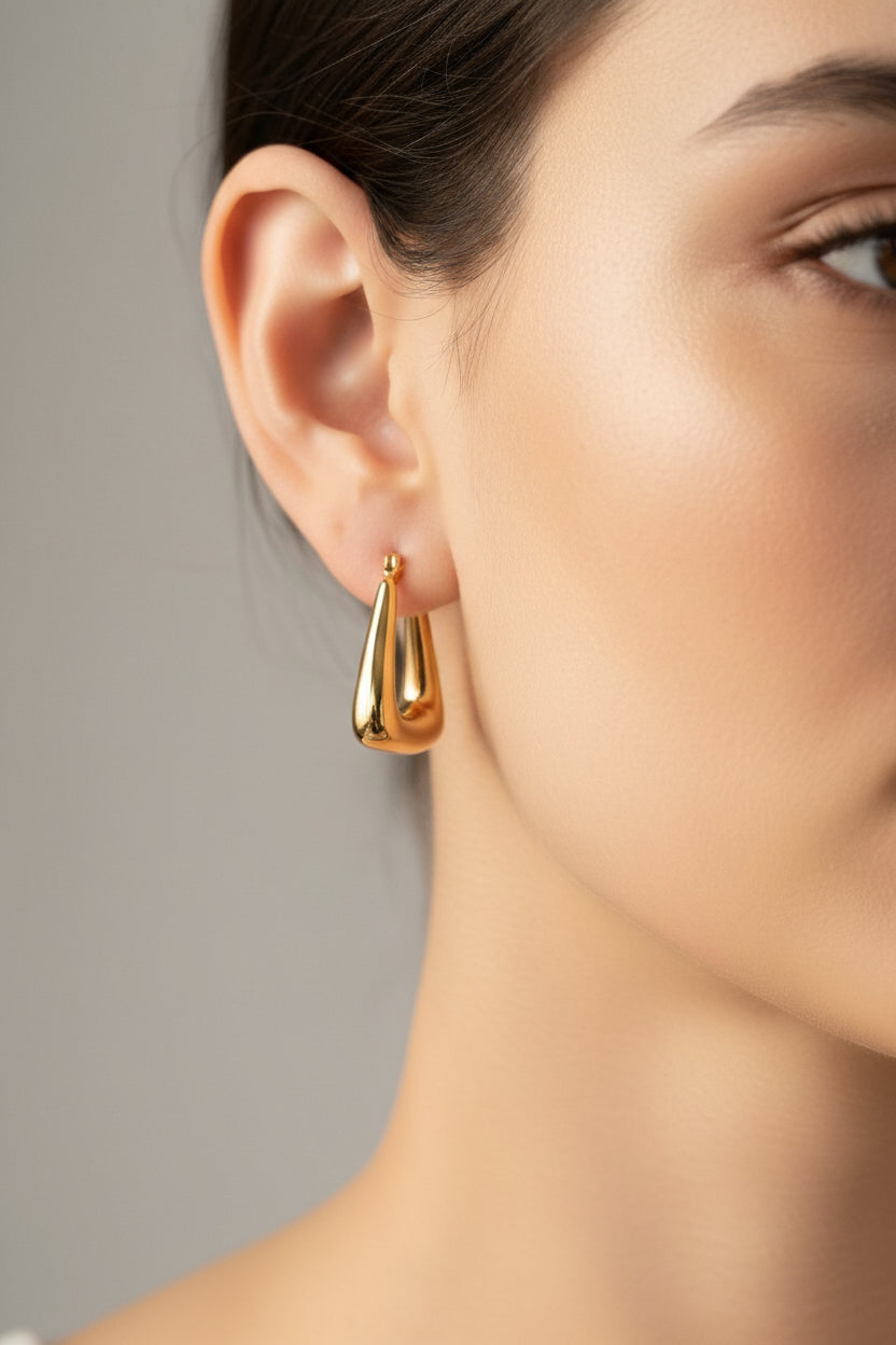 Close-up of geometric triangle gold hoop earrings in 18K PVD gold plating on model, GLISTIA water-safe jewellery