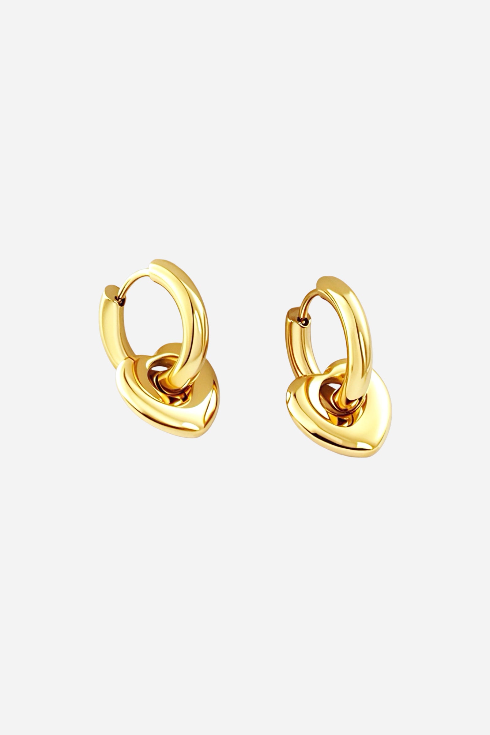Close-up of gold heart charm hoop earrings crafted from stainless steel with a lustrous PVD 18K gold-plated finish, showcasing smooth rounded hoops and a polished heart pendant – GLISTIA