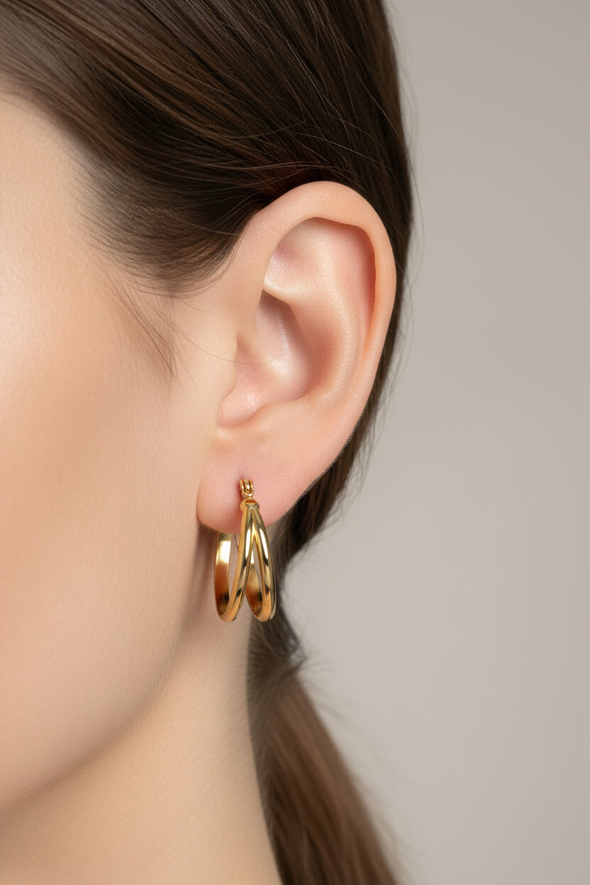 GLISTIA polished double hoop earrings in 18K PVD gold plated stainless steel worn on model ear.