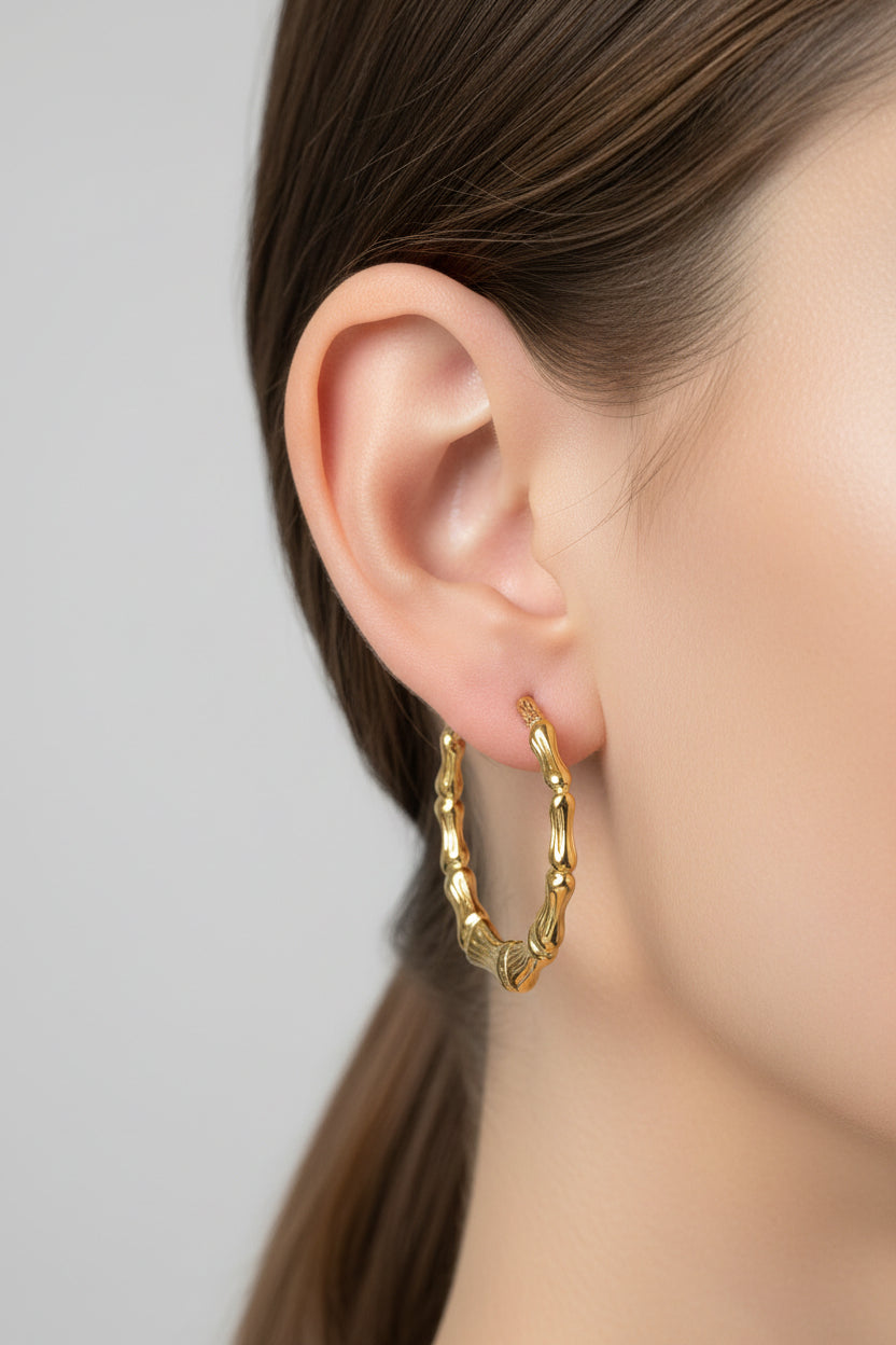Close-up of bamboo-style hoop earrings in 18K PVD gold plated stainless steel, showcasing a natural-inspired textured structure and modern silhouette