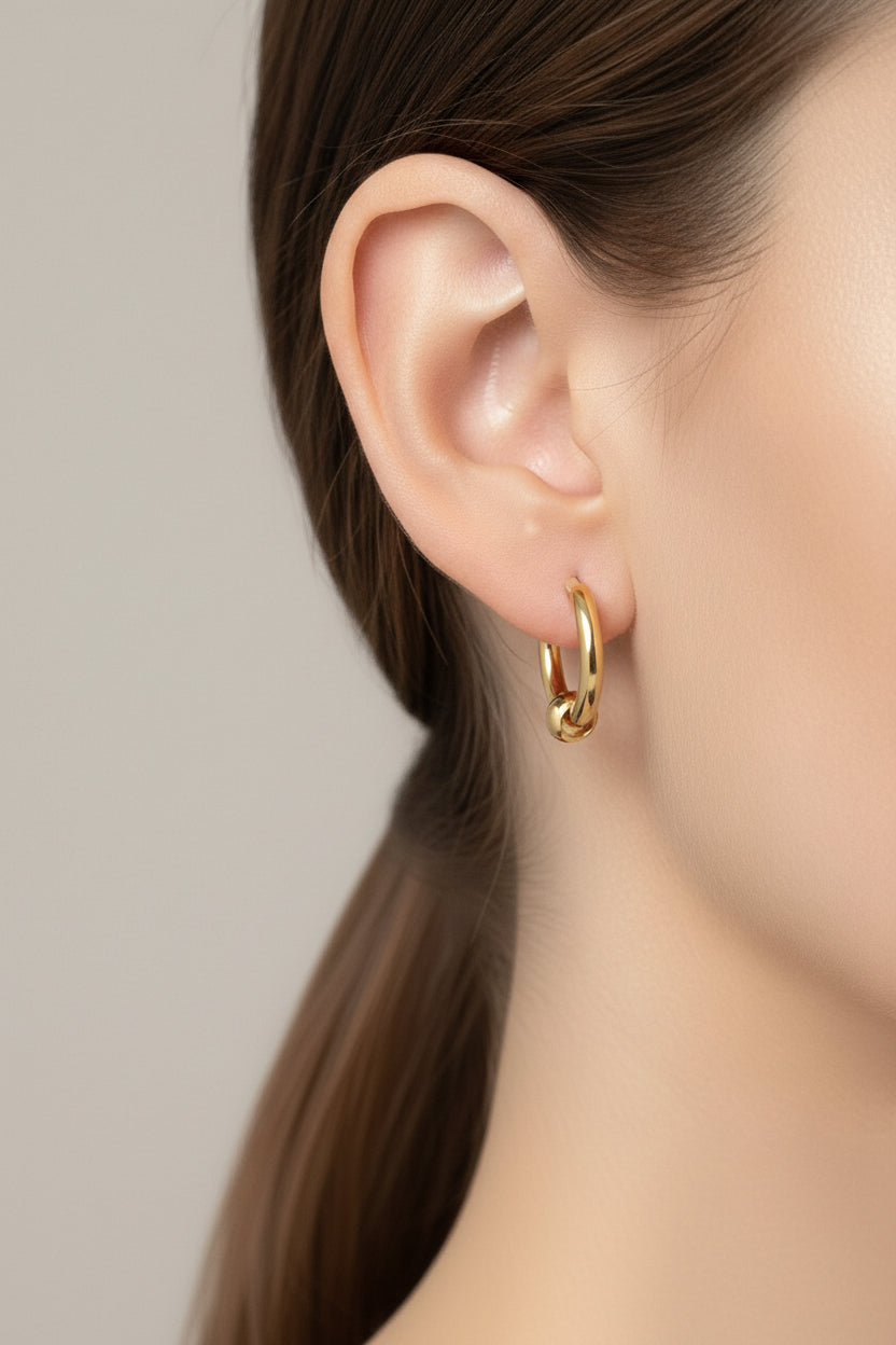 Close-up of hoop earrings with round bead accent in 18K PVD gold plated stainless steel, showcasing a minimalist polished finish and elegant detail