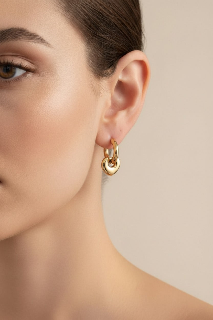 Gold heart charm hoop earrings crafted from stainless steel with 18K PVD gold plating, featuring a polished heart pendant and classic hoop design.