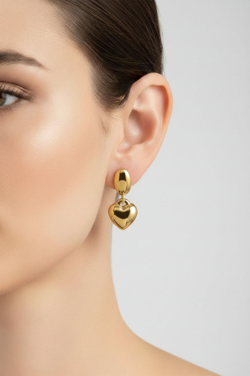 Close-up of gold dangle heart earrings showcasing high-shine 18K PVD gold plating and a polished heart drop design.