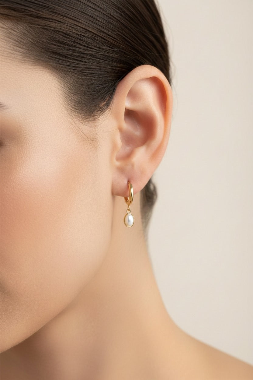 Gold oval drop hoop earrings crafted from stainless steel with 18K PVD gold plating, featuring a sleek oval charm suspended from polished hoops.