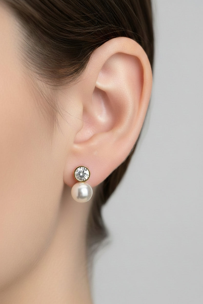 Close-up of pearl drop stud earrings showcasing polished 18K PVD gold plating, rhinestone accent, and luminous pearl-style drop.