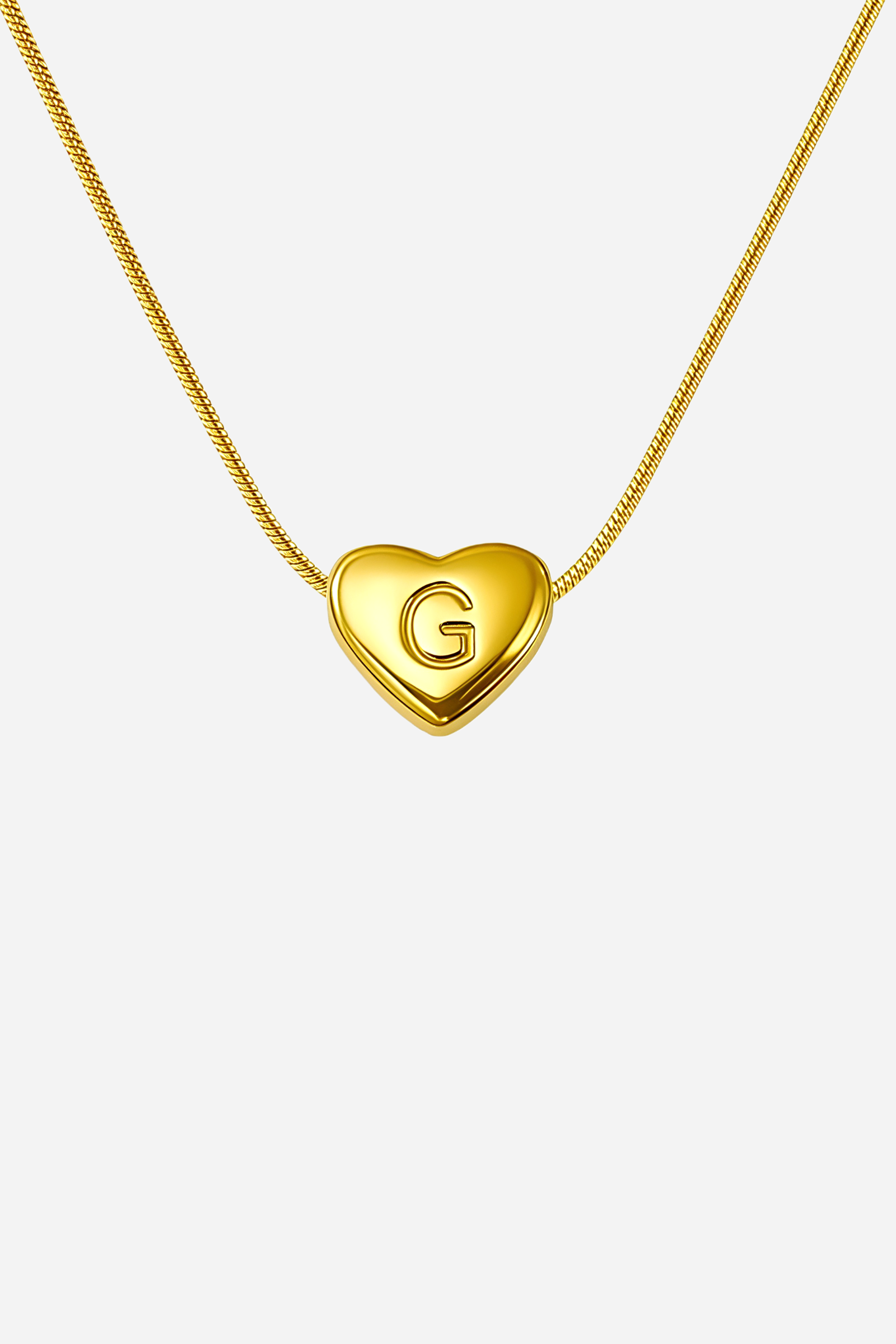 Close-up of heart-shaped initial ‘G’ pendant highlighting engraved letter and mirror-polished gold finish – GLISTIA