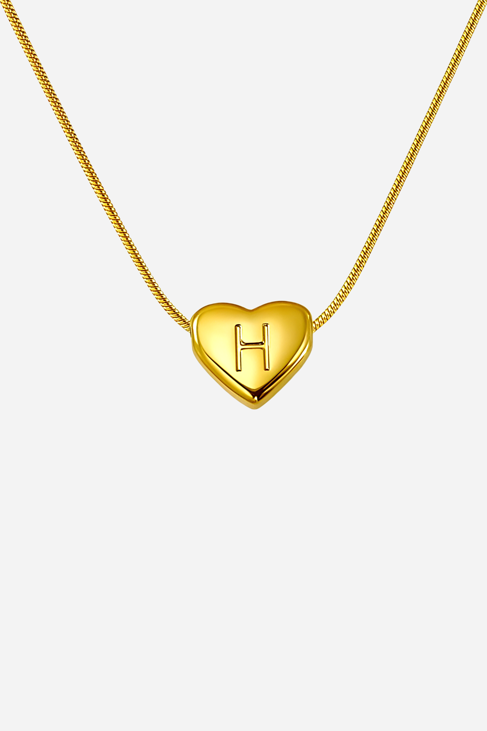Close-up of heart-shaped initial ‘H’ pendant highlighting engraved letter and mirror-polished gold finish – GLISTIA