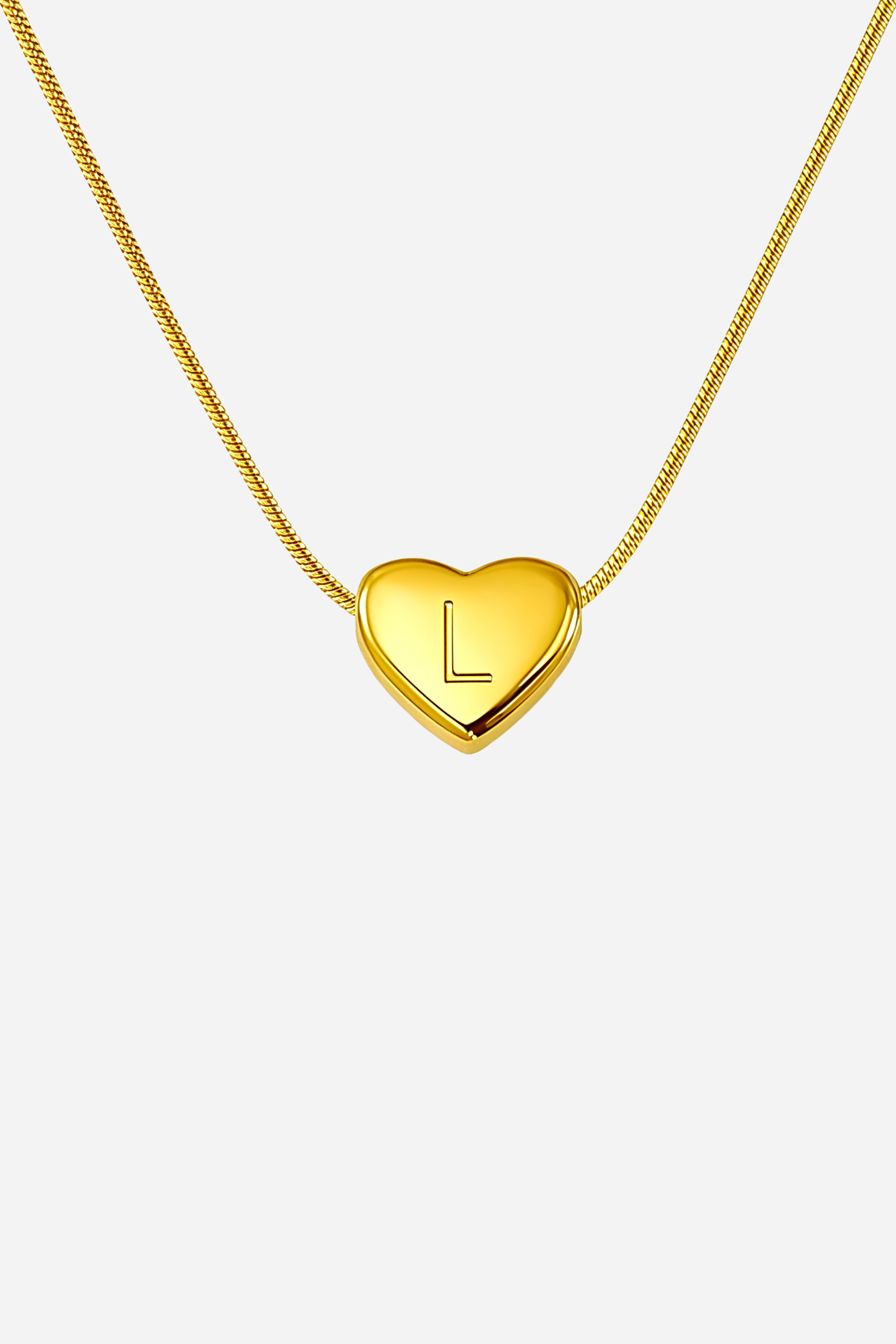 Close-up of heart-shaped initial ‘L’ pendant highlighting engraved letter and mirror-polished gold finish – GLISTIA