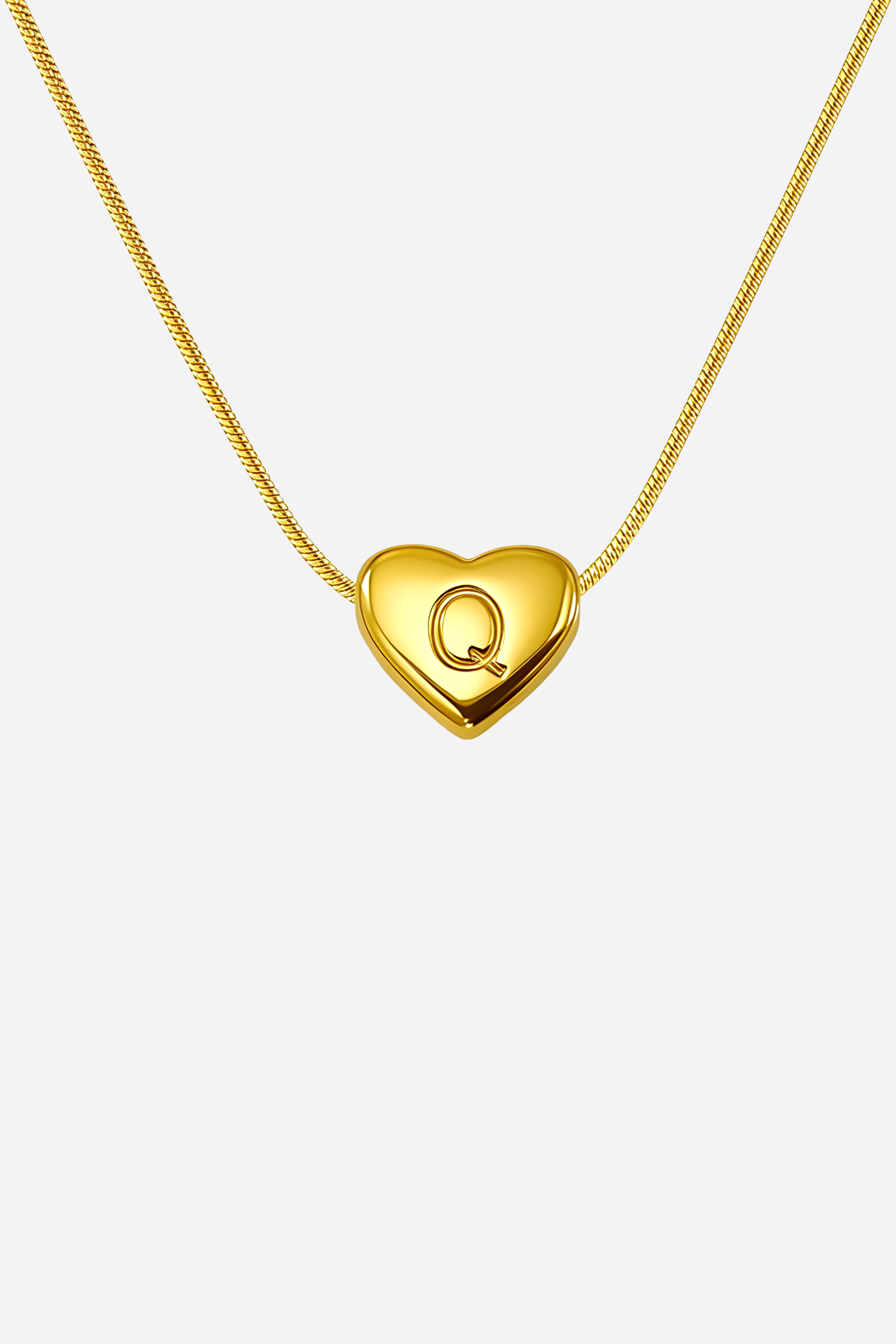 Close-up of heart-shaped initial ‘Q’ pendant highlighting engraved letter and mirror-polished gold finish – GLISTIA