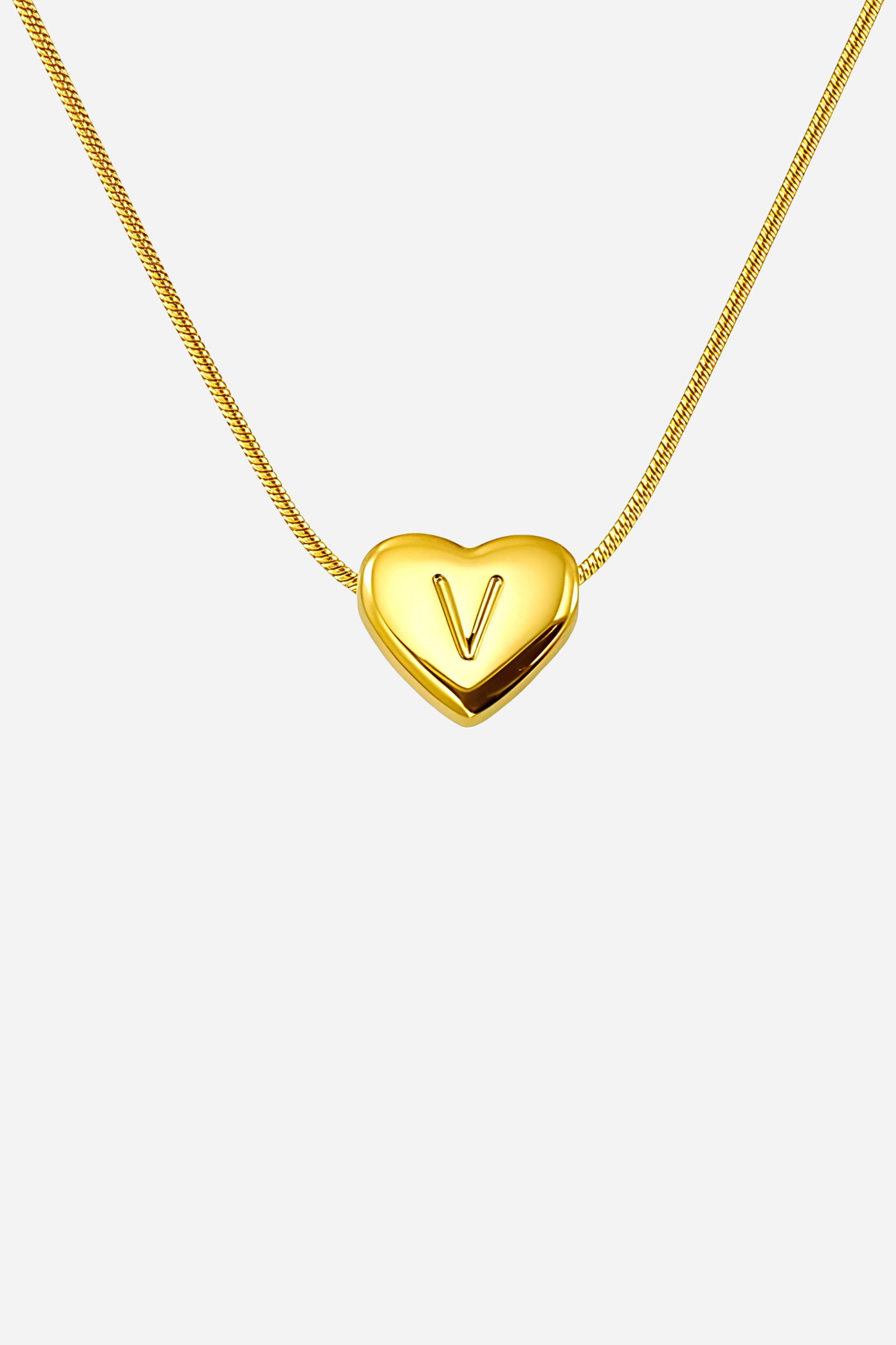 Close-up of heart-shaped initial ‘V’ pendant highlighting engraved letter and mirror-polished gold finish – GLISTIA
