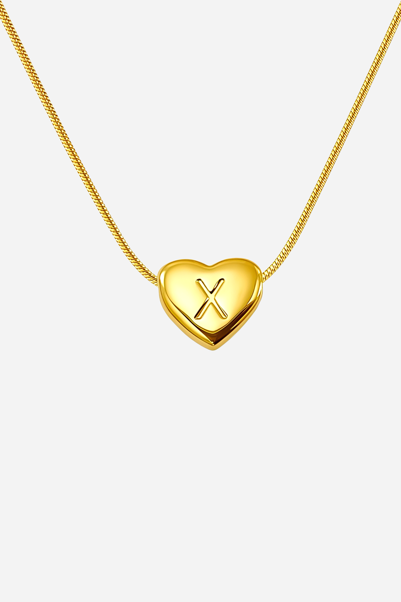 Close-up of heart-shaped initial ‘X’ pendant highlighting engraved letter and mirror-polished gold finish – GLISTIA
