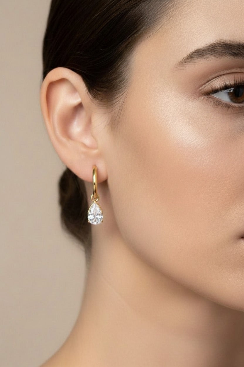 Gold teardrop crystal drop hoop earrings crafted from stainless steel with 18K PVD gold plating, featuring a clear teardrop-cut crystal and polished finish