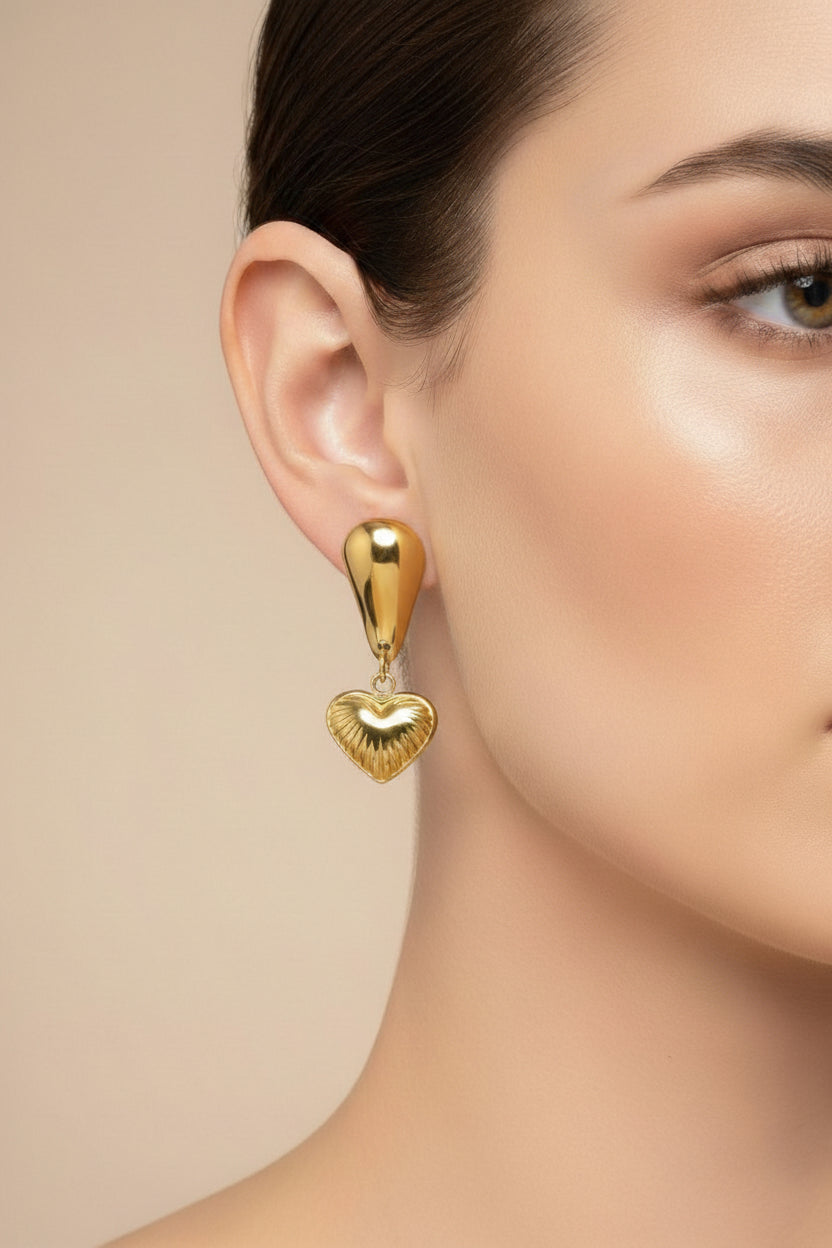 Close-up of textured heart drop earrings showcasing polished 18K PVD gold plating and intricate heart detailing.