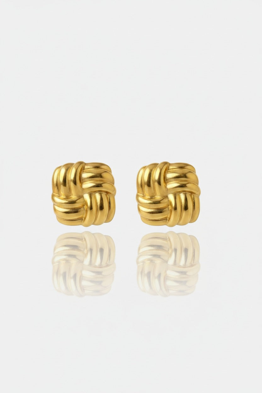 Gold woven square stud earrings in stainless steel with 18K PVD gold plating styled in a minimal editorial flat lay