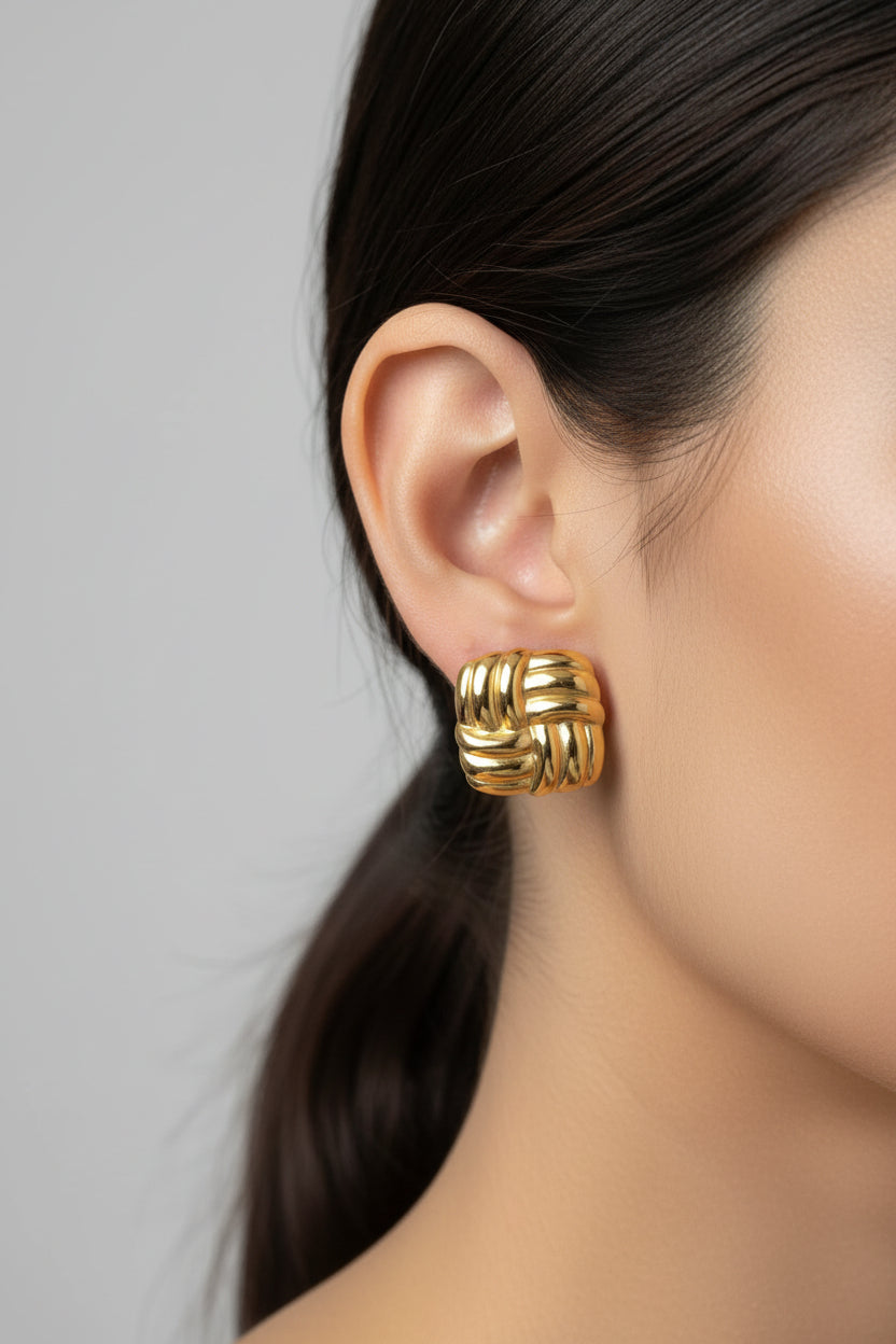 Gold woven square stud earrings worn on ear, showcasing textured square design with 18K PVD gold plated finish