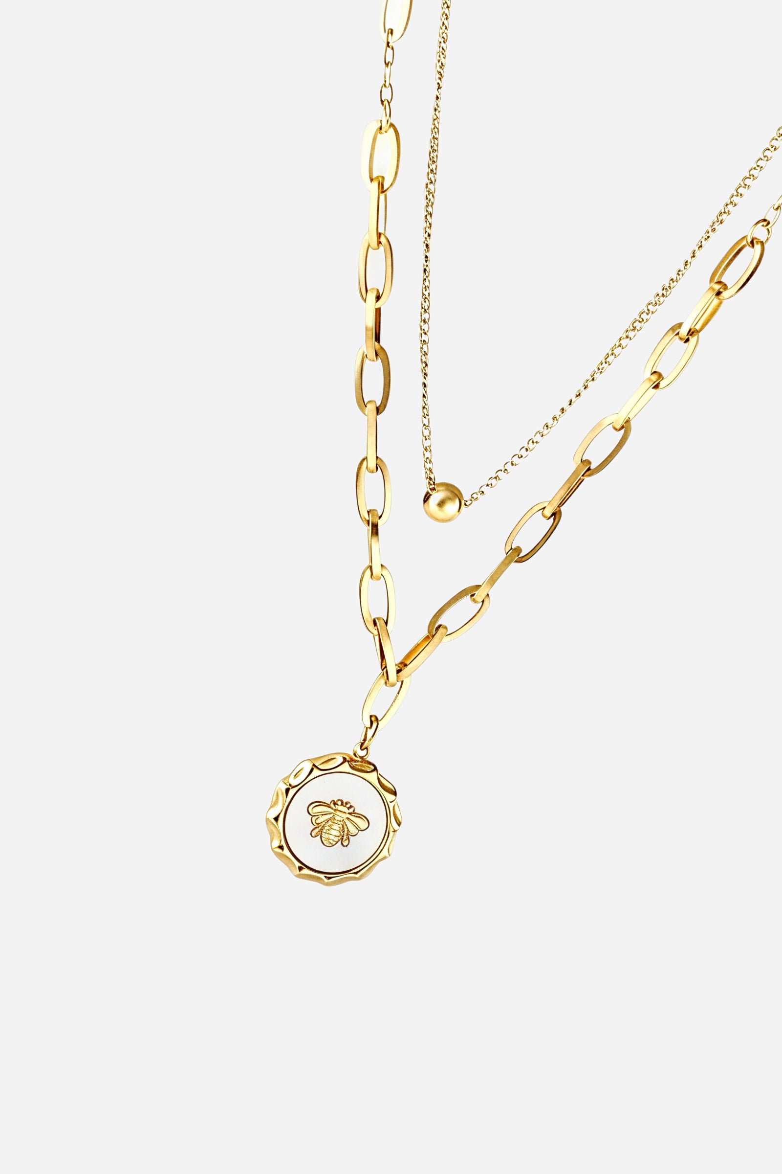 Close-up shot of GLISTIA bee medallion necklace with textured gold detailing.