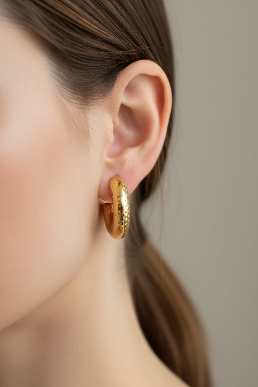 Close-up of hammered C-hoop earrings in 18K PVD gold plated stainless steel, showcasing a sculptural hammered texture and polished finish