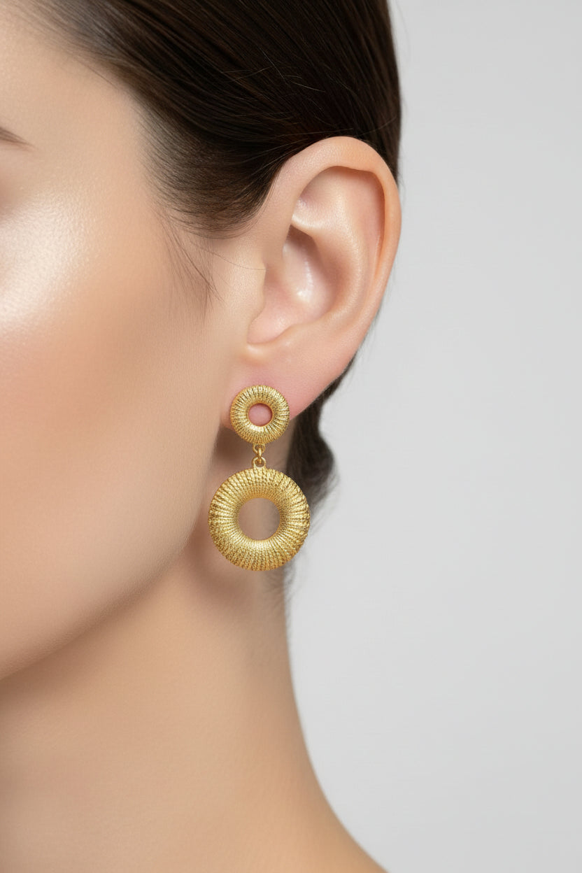Close-up of Liora Circle Drop Earrings showcasing textured detailing and a modern open circular silhouette in 18K PVD gold plating.
