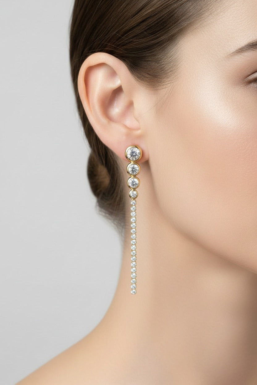 Long crystal drop earrings crafted from stainless steel with 18K PVD gold plating, featuring a cascading line of clear crystals.