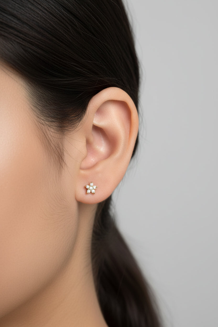 Dainty star crystal flat-back piercing earrings in 18K PVD gold plated stainless steel, shown on ear with subtle sparkle for everyday wear