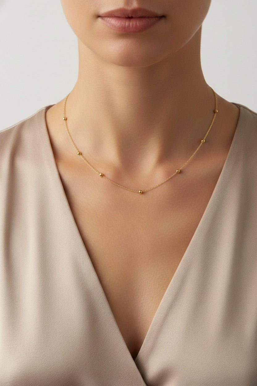 Minimalist gold bead chain necklace crafted from stainless steel with 18K PVD gold plating, worn on model neckline