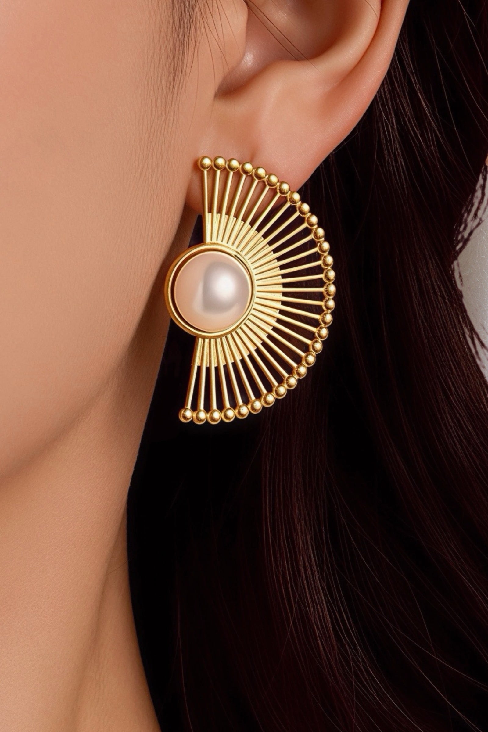 Model wearing radiant fan pearl earrings crafted from stainless steel with PVD 18K gold plating, featuring a bold half-fan silhouette and luminous central pearl – GLISTIA.