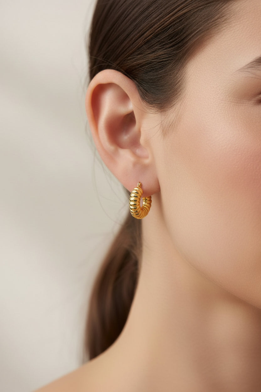 Textured ribbed gold hoop earrings 18K PVD gold plated on model ear, modern stainless steel hoop earrings close up