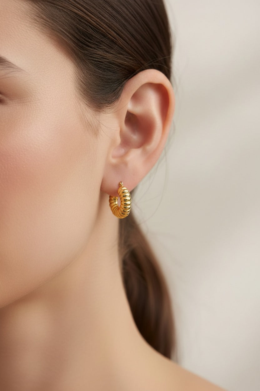 Ribbed textured hoop earrings in 18K PVD gold plating worn on ear, stainless steel gold hoops with sculptural ribbed design