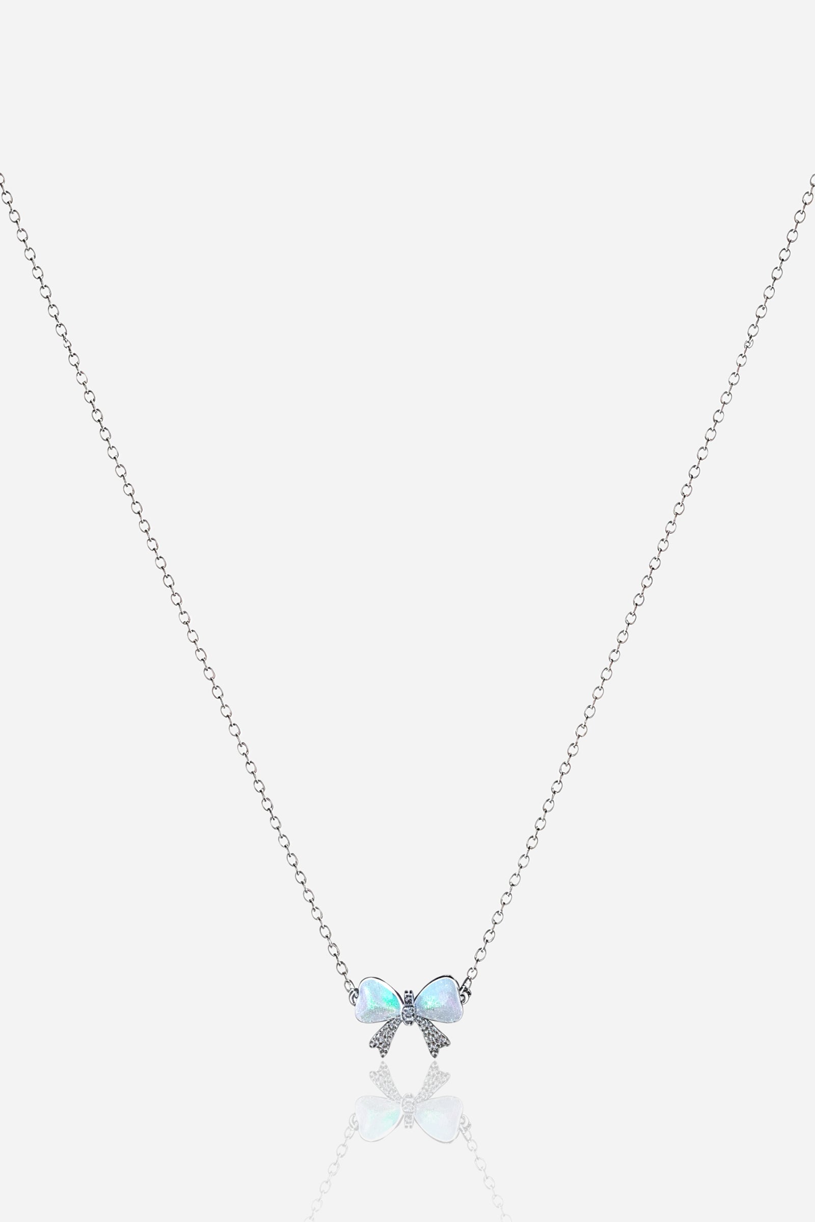 Zoom view of silver bow pendant with pearlescent hearts and crystal accents on stainless steel chain – GLISTIA
