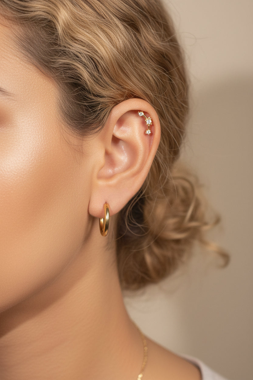 Star curve crystal stud earrings worn on ear, showcasing curved bar star design with cubic zirconia stones in gold plated stainless steel