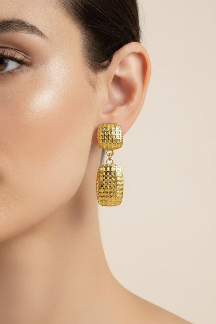 Textured geometric drop earrings crafted from stainless steel with 18K PVD gold plating, featuring a polished stud and rectangular grid-pattern drop.